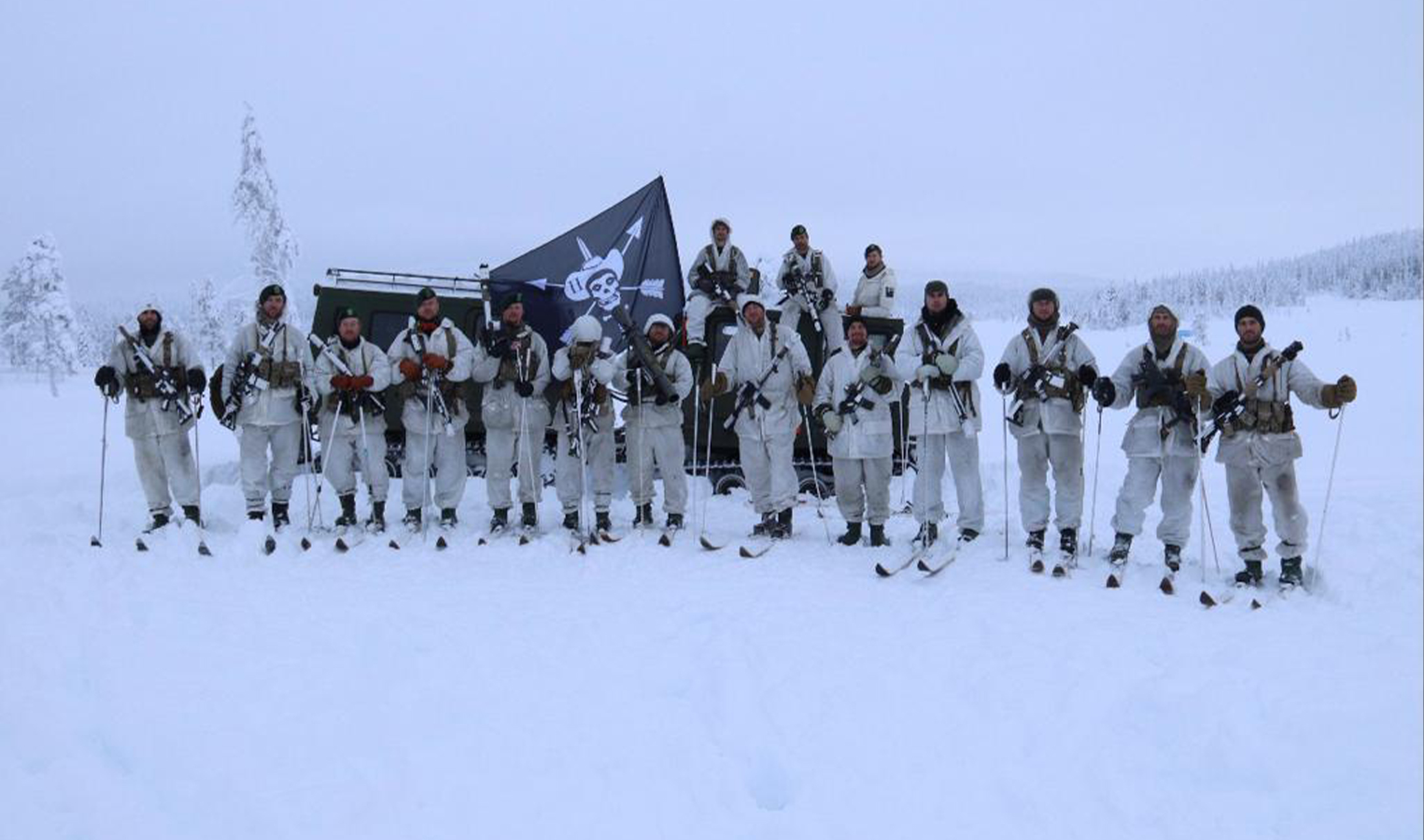 Men in military uniforms holding flags and rifles standing in snow.