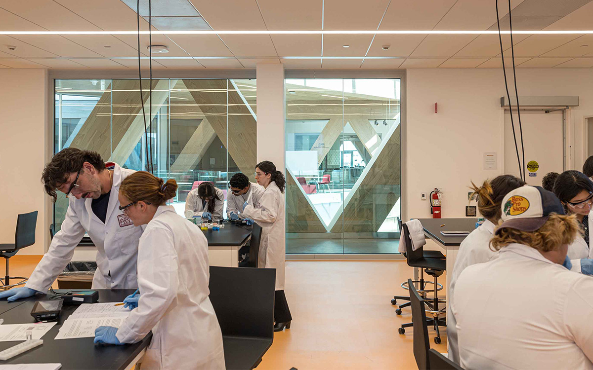 A busy lab at the Robert Day Sciences Center, with students in lab coats working in groups.