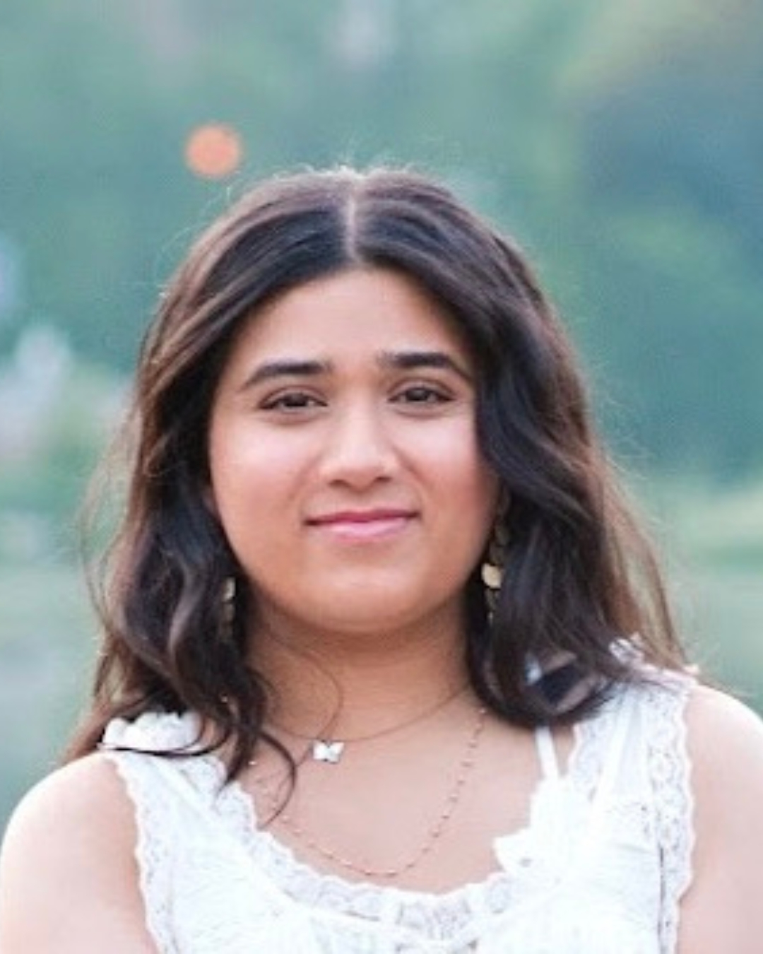 Girl with brown curly short hair and white top. 