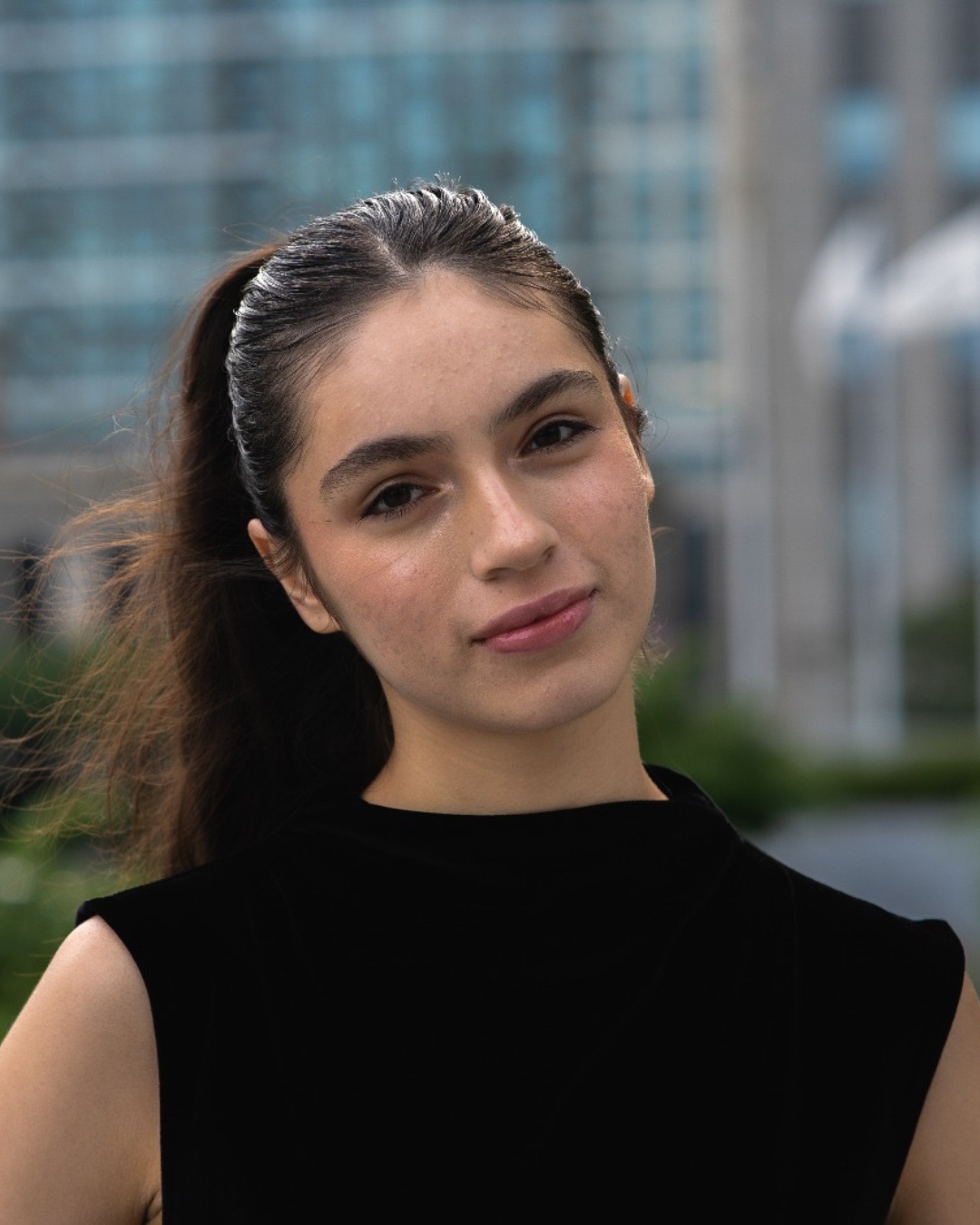 Girl wearing black top with long black hair in pony tail.