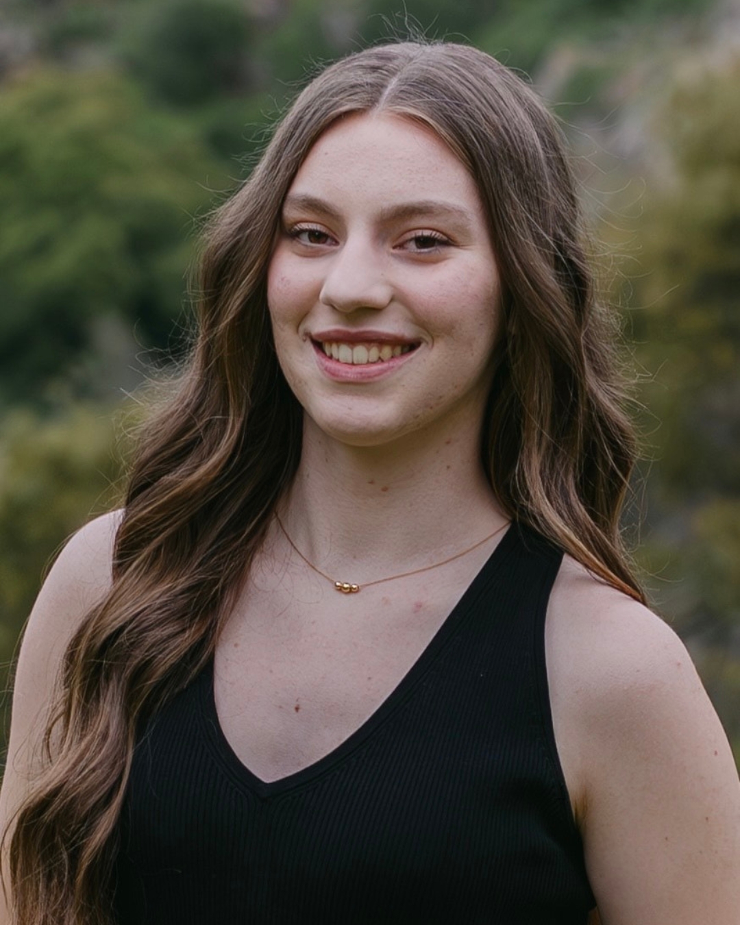 Gril wearing black tank top with long brown curly hair. 