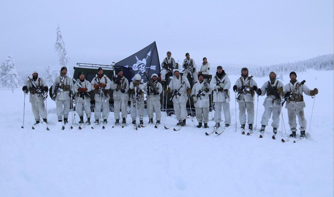 Men in military uniforms holding flags and rifles standing in snow.