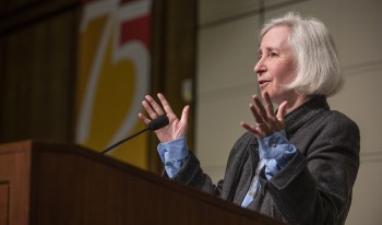 Martha Minow addresses attendees from the Ath podium. Behind her hangs a 75th Anniversary banner.