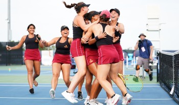 Athenas Tennis Team celebrates with a jubilant group hug on the court after their win.