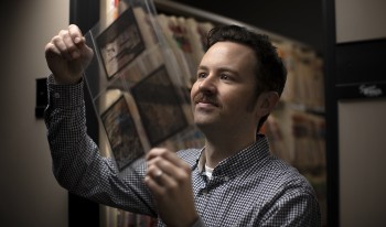 CMC Archivist Sean Stanley holding up photos from the school archive