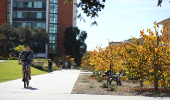 Student riding bike across campus during Fall