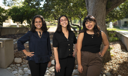 2021 Ath Fellows pose with hands on their hips, lined up prom-style, under the shade of a tree on campus