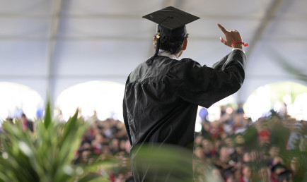 A CMC grad waves to the crowd inside the white tent after they walked the commencement stage during Classes of 2020 &amp; 2021's Celebration Weekend.