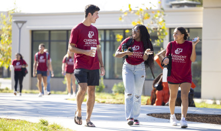 Students who arrived early to campus walk by Collins in their CMC maroon t-shirts.