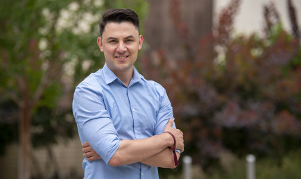 Ramon Torres ’08 photographed outdoors with red and green foliage.