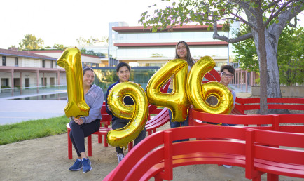 Students near the Jeppe Hein benches hold giant gold balloons spelling out "1946"