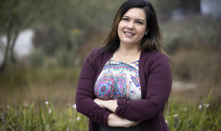 Assistant Professor Jennifer Feitosa photographed outdoors with flowers