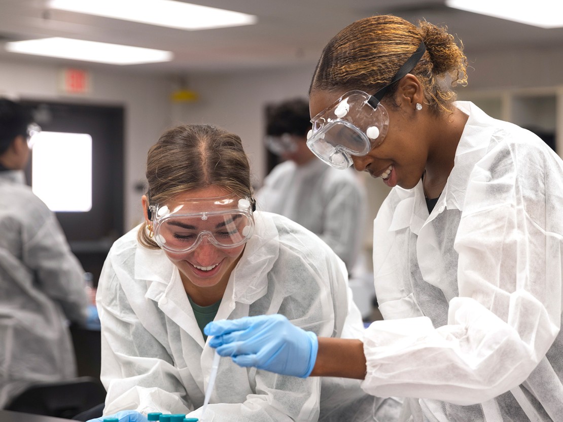 Two students working with tubs in a lab.