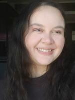 Woman with long curly hair wearing black top taking a selfie.